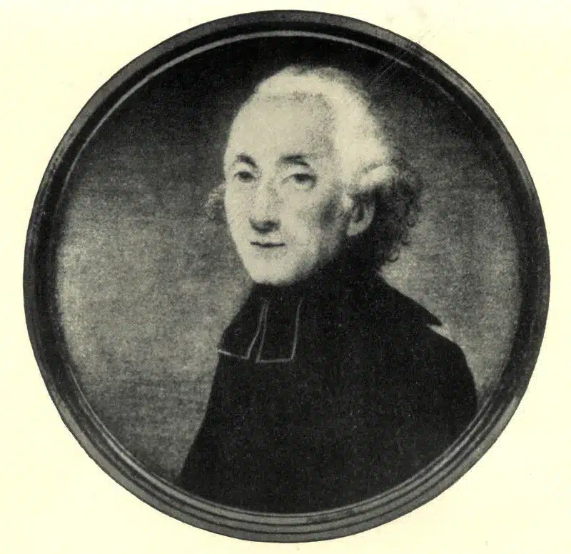 A black and white portrait of an older man with white hair, wearing dark clothing with a high collar, shown in profile against a plain background.